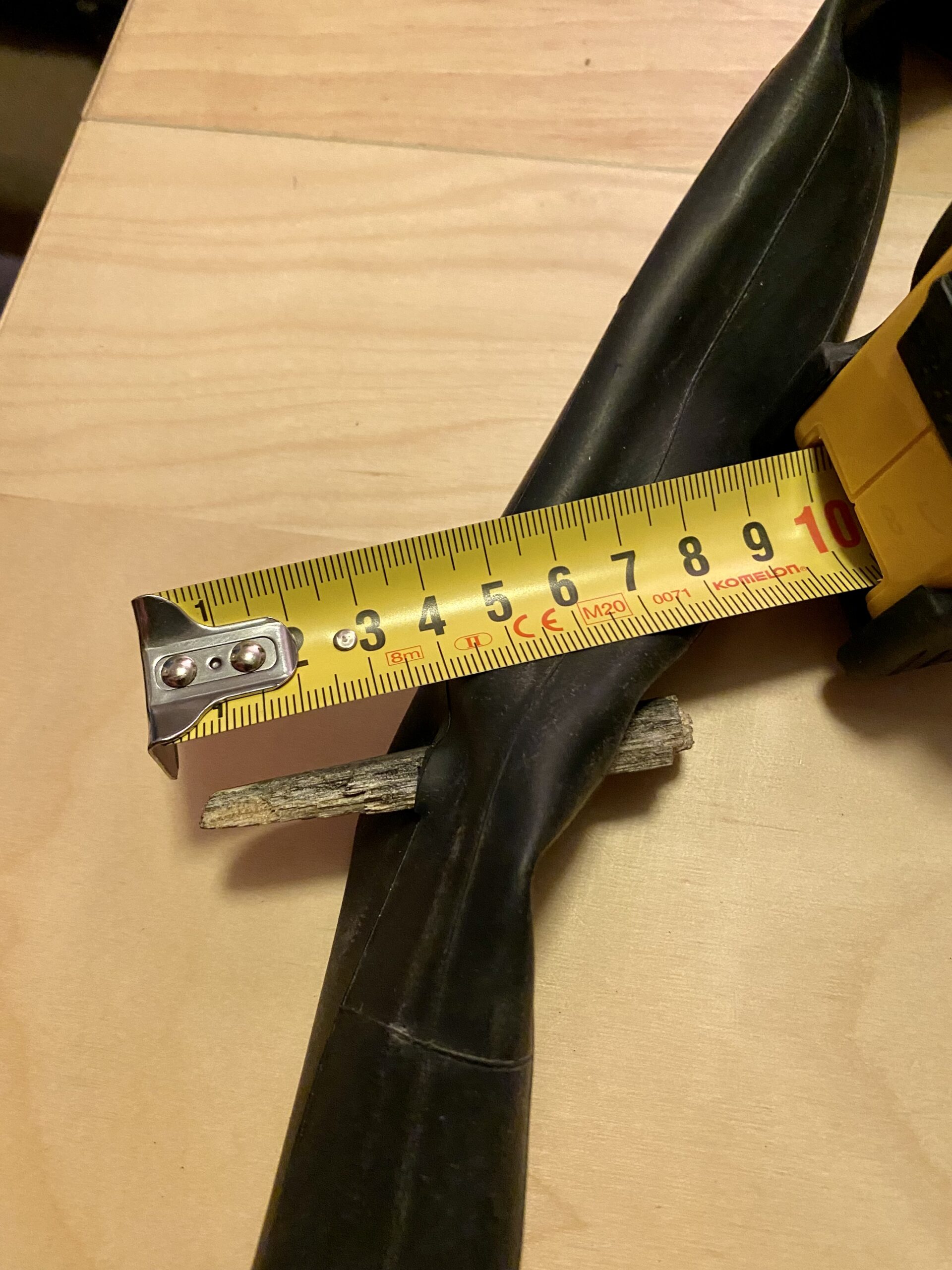 A large shard of wood pushed completely through an inner tube. There is a tape measure next to the shard measuring it at 7 mm.