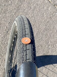 A bicycle tire is still on the bike. A roofing nail firmly embedded.