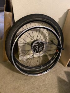 An eBike wheel, leaned against a wall. A bike rim, leaned against that.