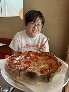 My child giving the ubiquitous V-sign at a pizza.