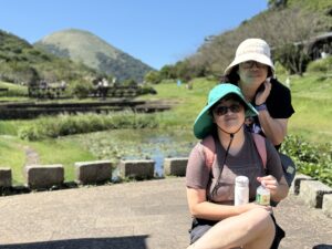 Two humans and grassy hills behind